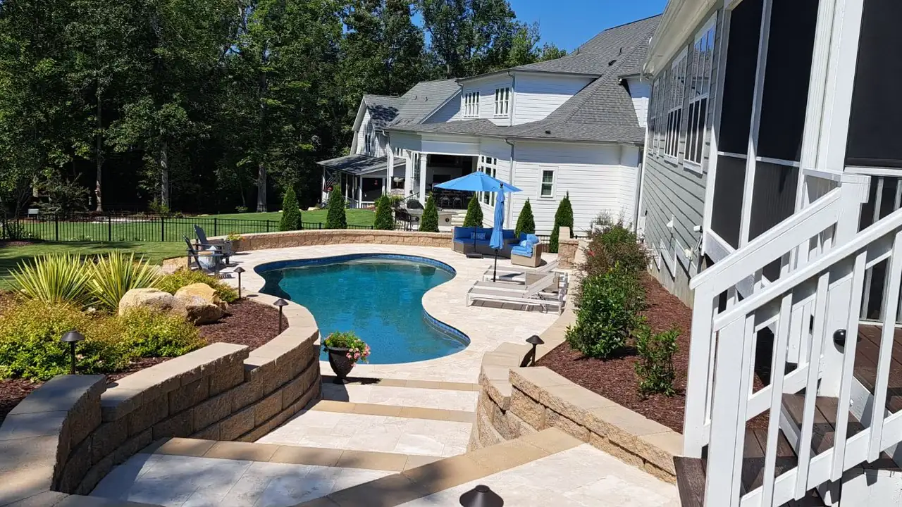 Finished pool and raised spa with a natural stone waterfall and travertine coping
