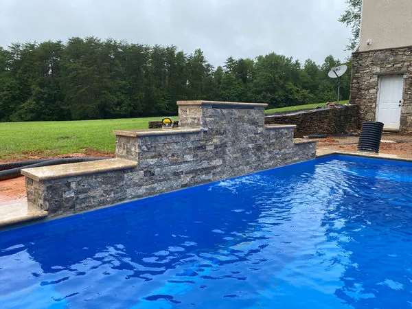 Stacked stone veneer wall and seating surround at a new pool