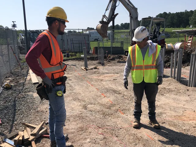 Crew grading and preparing a site with survey equipment before concrete is placed