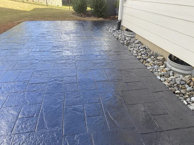Stamped concrete surface with a tooled border running beside a gravel drainage strip
