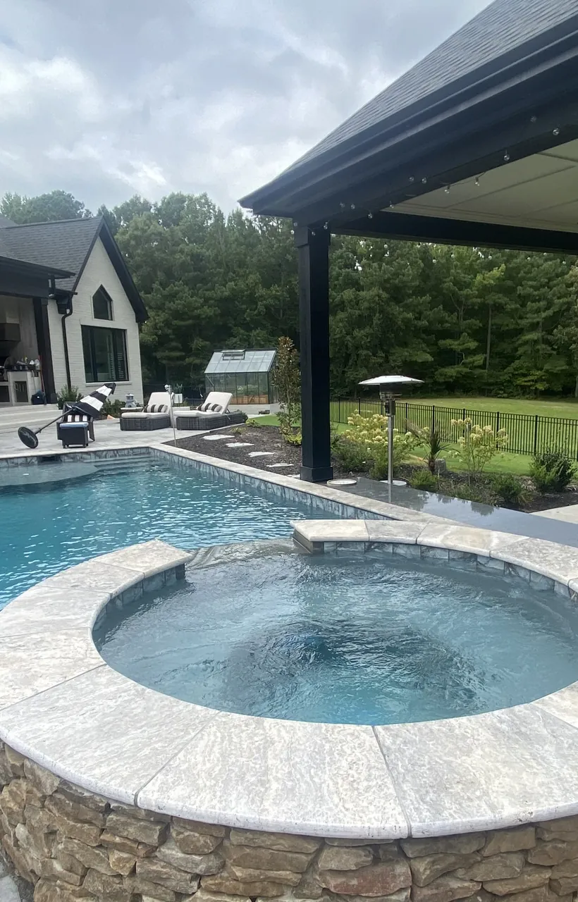 Pool and raised spa under a covered patio with stone decking