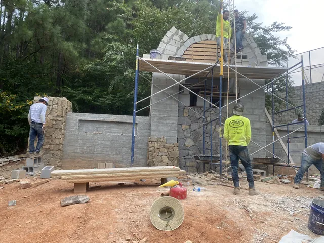 Crew laying stone on a wall being built on site
