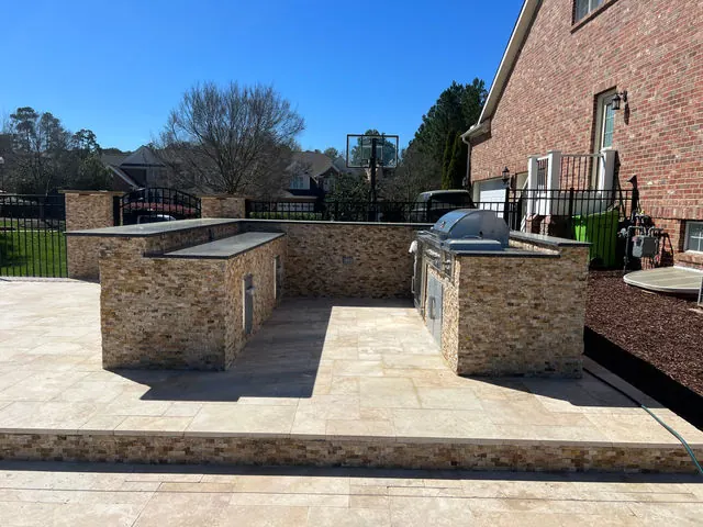 Stone veneer outdoor kitchen with travertine decking