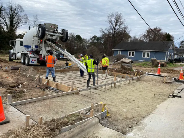 Barcenas and Sons crew placing concrete from a mixer truck over rebar and forms